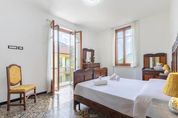 A hotel room with a bed, a chair, a desk, a mirror, and a window.
