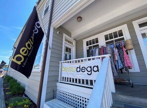 Ein Gebäude mit einem Schild, auf dem 'beau dega' steht, und Kleidung, die auf der Veranda ausgestellt ist.