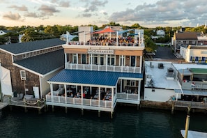 Un restaurant situé au bord de l’eau, doté d’une terrasse, d’un quai et d’un bâtiment sur lequel on peut lire l’inscription « MOONRAKERS ».