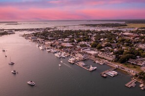Vue aérienne d’une ville côtière avec un port de plaisance, des bâtiments donnant sur le front de mer et un pont en arrière-plan.