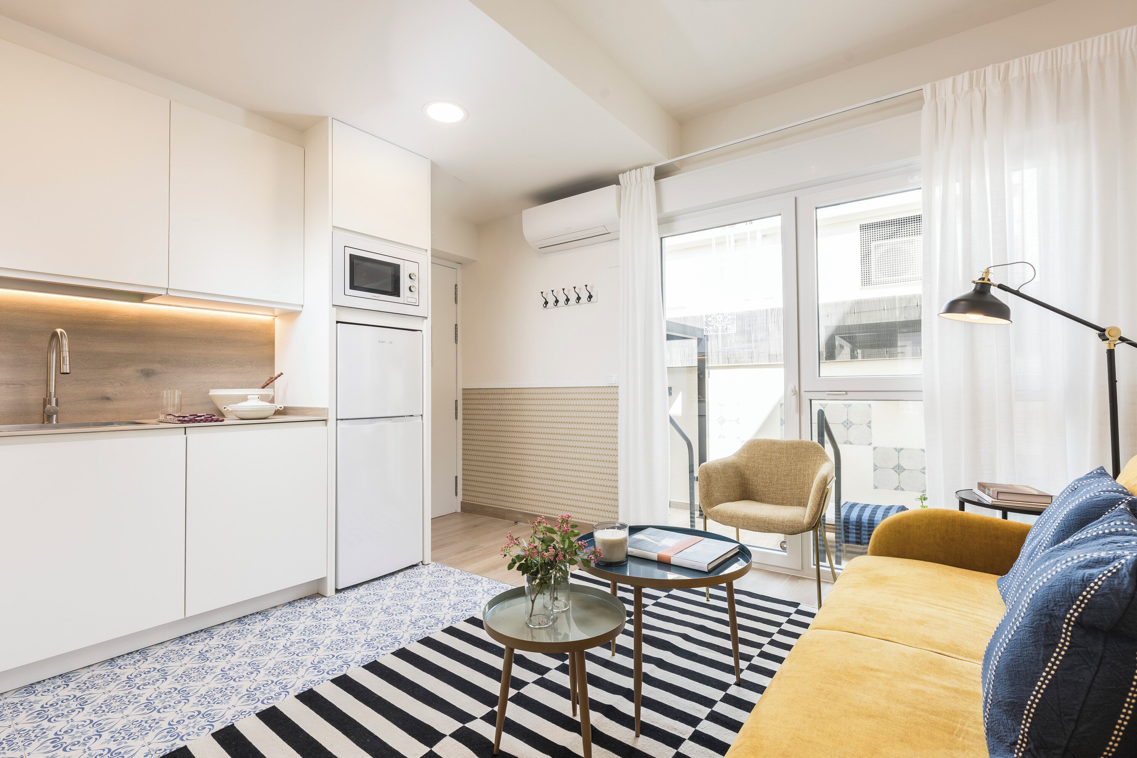 Un espacio habitable moderno con cocina, sofá, mesa de centro y una silla.
