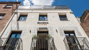 Un edificio con un letrero que dice 'Sambara Living', balcones con barandillas de metal y paneles solares en el techo.
