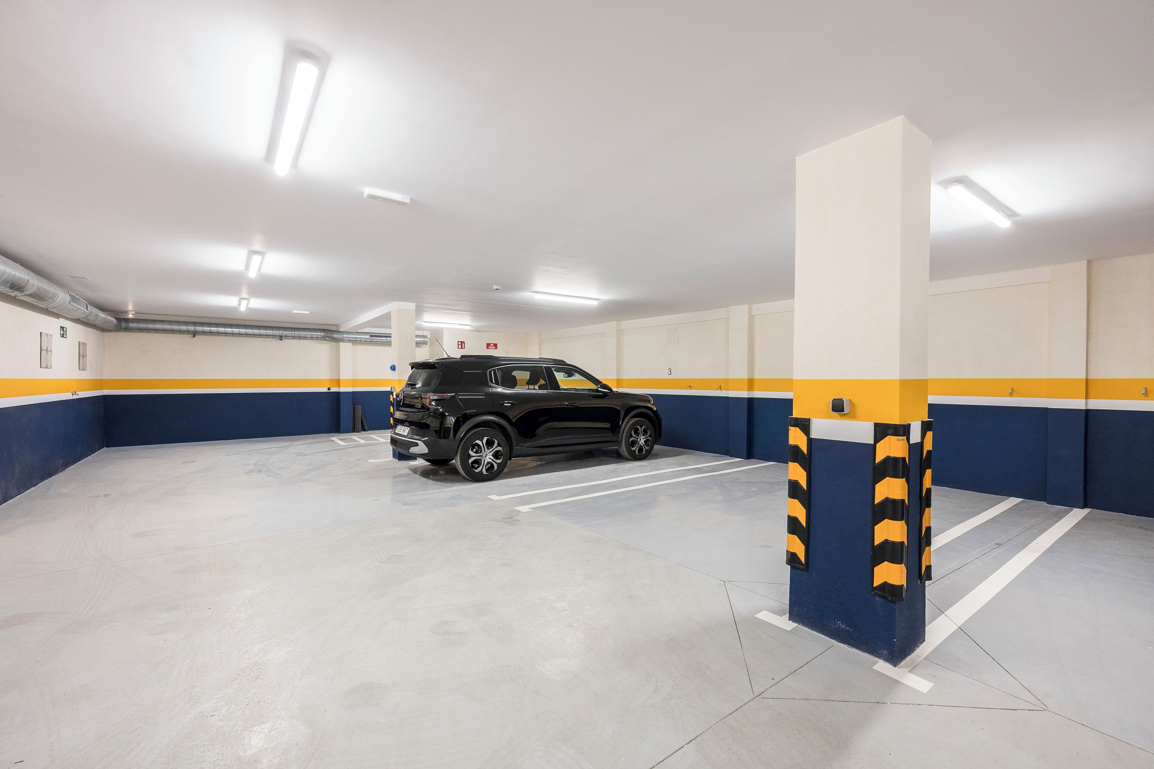 A parking garage with a black SUV parked in a space marked with the number 3.