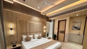 Une chambre d’hôtel moderne avec un grand lit, une table de chevet, une commode, un miroir et un luminaire fixé au mur.