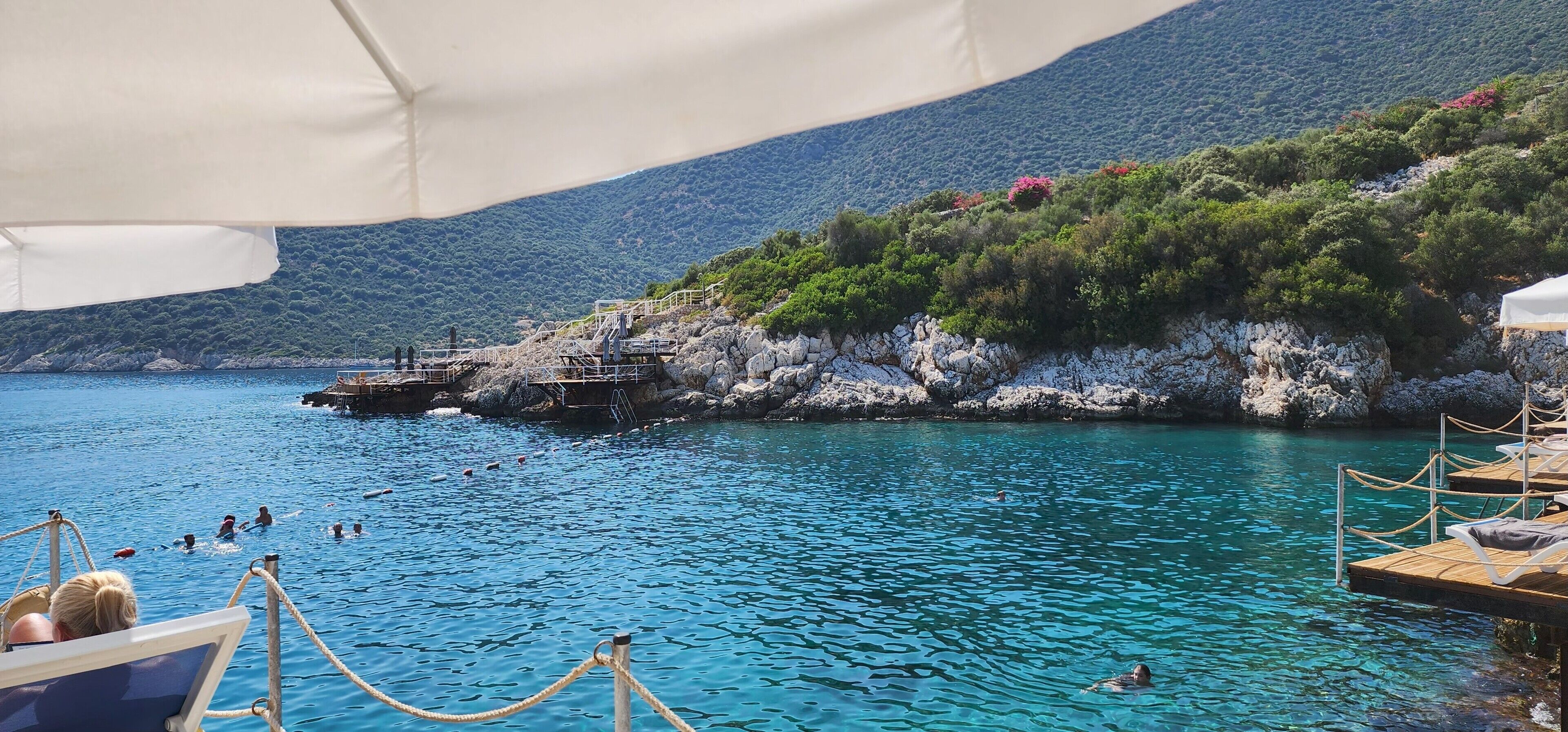 A coastal area with clear blue water, rocky cliffs, and a boat dock.