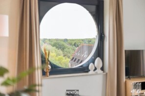 A round window with a view of a green landscape and buildings. - Sialamer - cozy seaside apartment with sunny terrace (De Panne)
