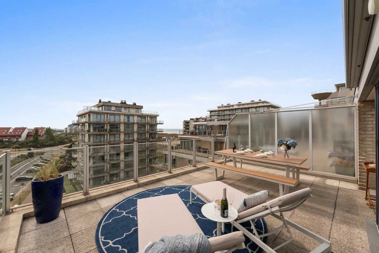 Ein Balkon mit rundem Tisch, Lounge-Sesseln und einer Topfpflanze.