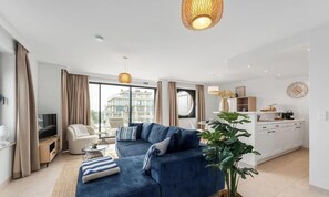 Ein modernes Wohnzimmer mit Sofa, Fernseher und Essbereich.