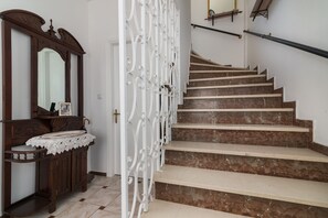 Eine Treppe mit Marmorstufen, eine hölzerne Bank mit Spitzentuch und ein weißes Ziergitter.