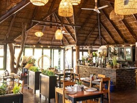 Un restaurante interior con mesas y sillas de madera, y un techo de paja.
