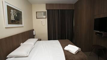 Habitación de hotel con cama, televisión, un cuadro en la pared y teléfono.