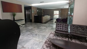 Un vestíbulo moderno con mostrador de recepción, zona de estar y pared de vidrio.