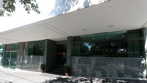 Un edificio moderno con fachada de vidrio, un acceso cubierto y una escalera que lleva a la entrada.