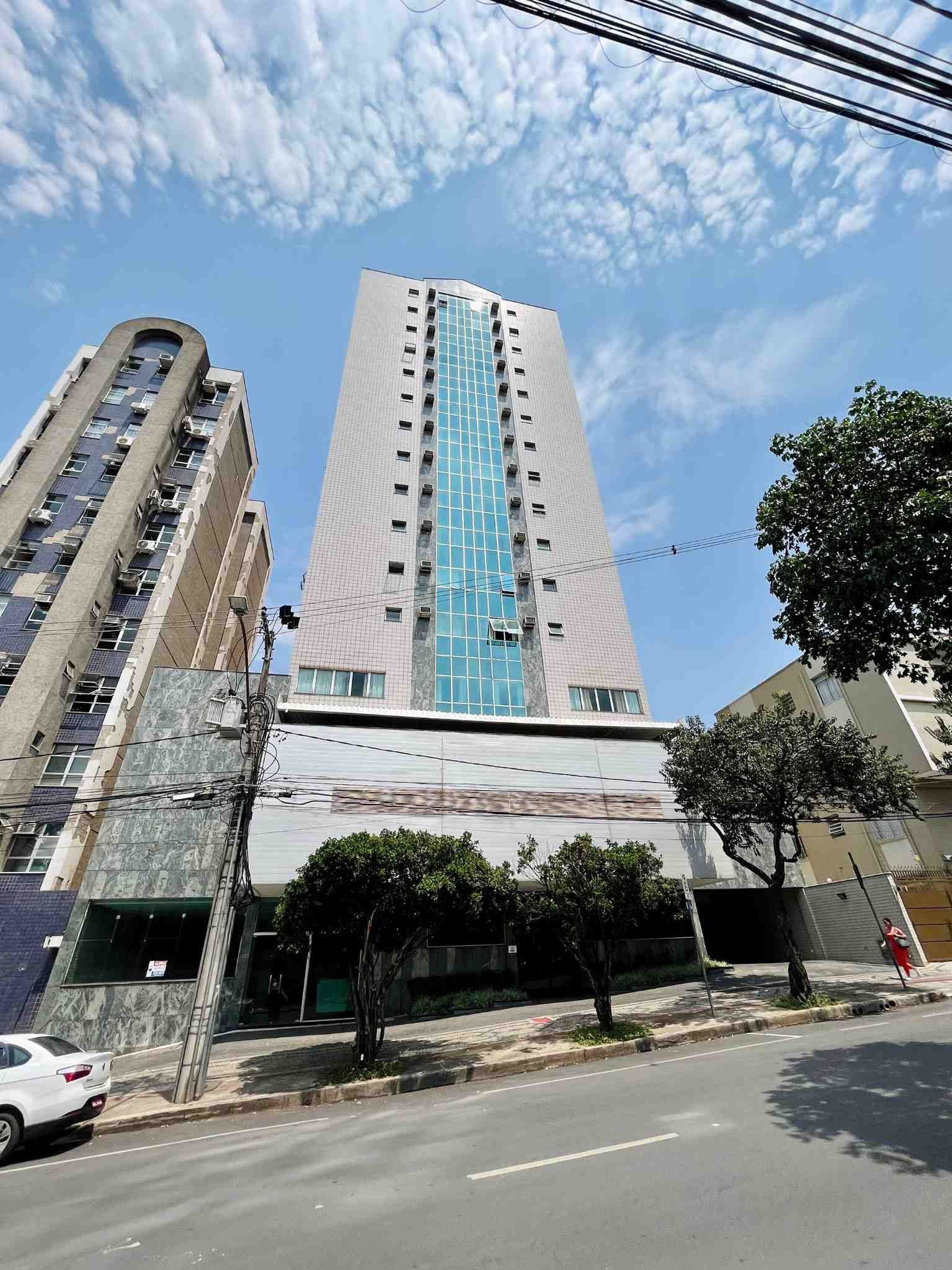 Un edificio alto con fachada central de vidrio y varios pisos.