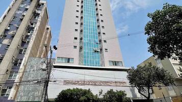 Un edificio alto con fachada central de vidrio y varios pisos.