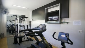 Un gimnasio con cintas de correr, máquinas de pesas y un espejo grande.