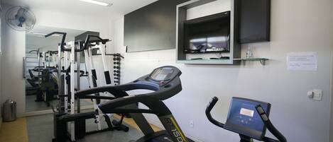 A gym with treadmills, weight machines, and a mirrored wall.