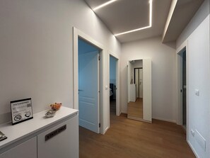 A hallway with wooden flooring, white walls, and blue doors. There is a reception desk with a sign indicating it's for staff only. - 4BNB - Stiv's Apartment (Rome)