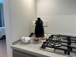 A kitchen with a gas stove, a coffee maker, and two glass bowls on the countertop. - 4BNB - Stiv's Apartment (Rome)