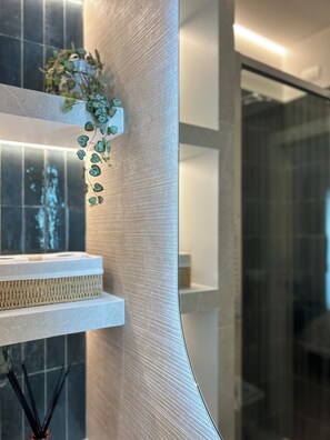 A modern bathroom with a textured wall, a shelf with a plant, and a glass shower enclosure. - 4BNB - Stiv's Apartment (Rome)