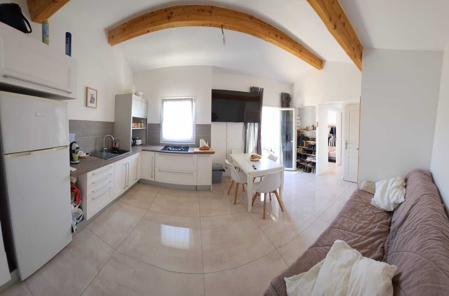 Una cocina compacta con comedor, un sofá y una televisión.