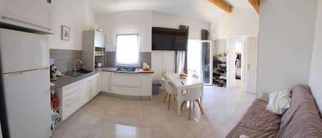Una cocina compacta con comedor, un sofá y una televisión.