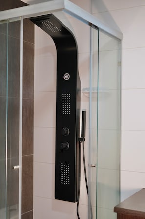 A modern shower enclosure with a curved design, a control panel with multiple settings, and a glass door.