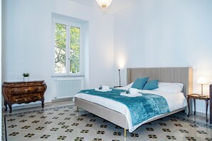 Ett sovrum med en säng, en byrå, ett fönster och en lampa.