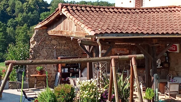 Un edificio rústico con techo de tejas, paredes de piedra y valla de madera adornada con flores.