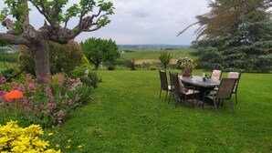 Un jardin avec une table et des chaises, entouré de différentes plantes et fleurs.