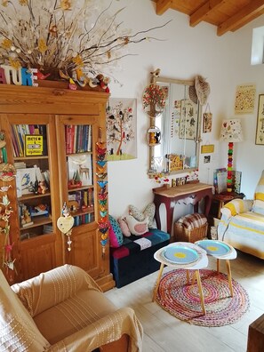 Un salon chaleureux avec un meuble en bois, une bibliothèque, une table basse ronde, un canapé à rayures et un tapis coloré.