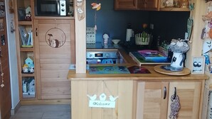 Une cuisine en bois avec une pancarte « Bienvenue », des placards en bois et divers appareils de cuisine.