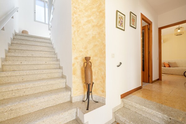 A staircase with a textured wall, a door leading to a room, and a small table with a vase.