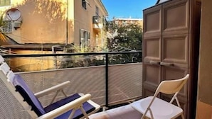 A balcony with two chairs, a view of a building, and a door. - Hostdomus - Cozy corner near the sea (Finale Ligure)