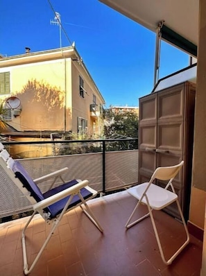Un balcone con due sedie, vista su un edificio e una porta.