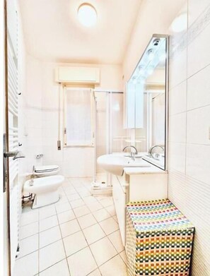 Un baño con inodoro, bidé, lavamanos y espejo.