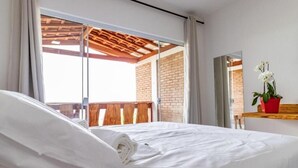 Una habitación de hotel con cama, ventana y una planta en maceta.