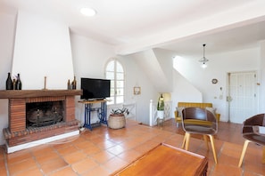A spacious living room with a fireplace, a television, and a large window.