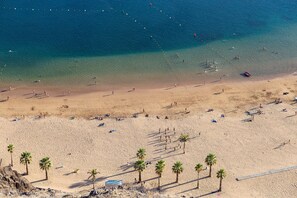Una playa con agua cristalina, palmeras y gente.