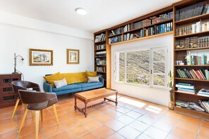 A living room with a sofa, chairs, a coffee table, a bookshelf, and a window with a view.