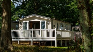 A mobile home with a deck, surrounded by trees. - Charming Isle of Wight Holiday Park Retr (Cowes)