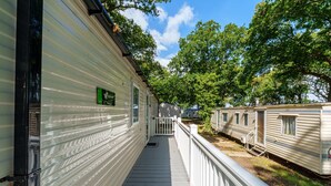 A row of mobile homes with a wooden deck and white railings. - Charming Isle of Wight Holiday Park Retr (Cowes)