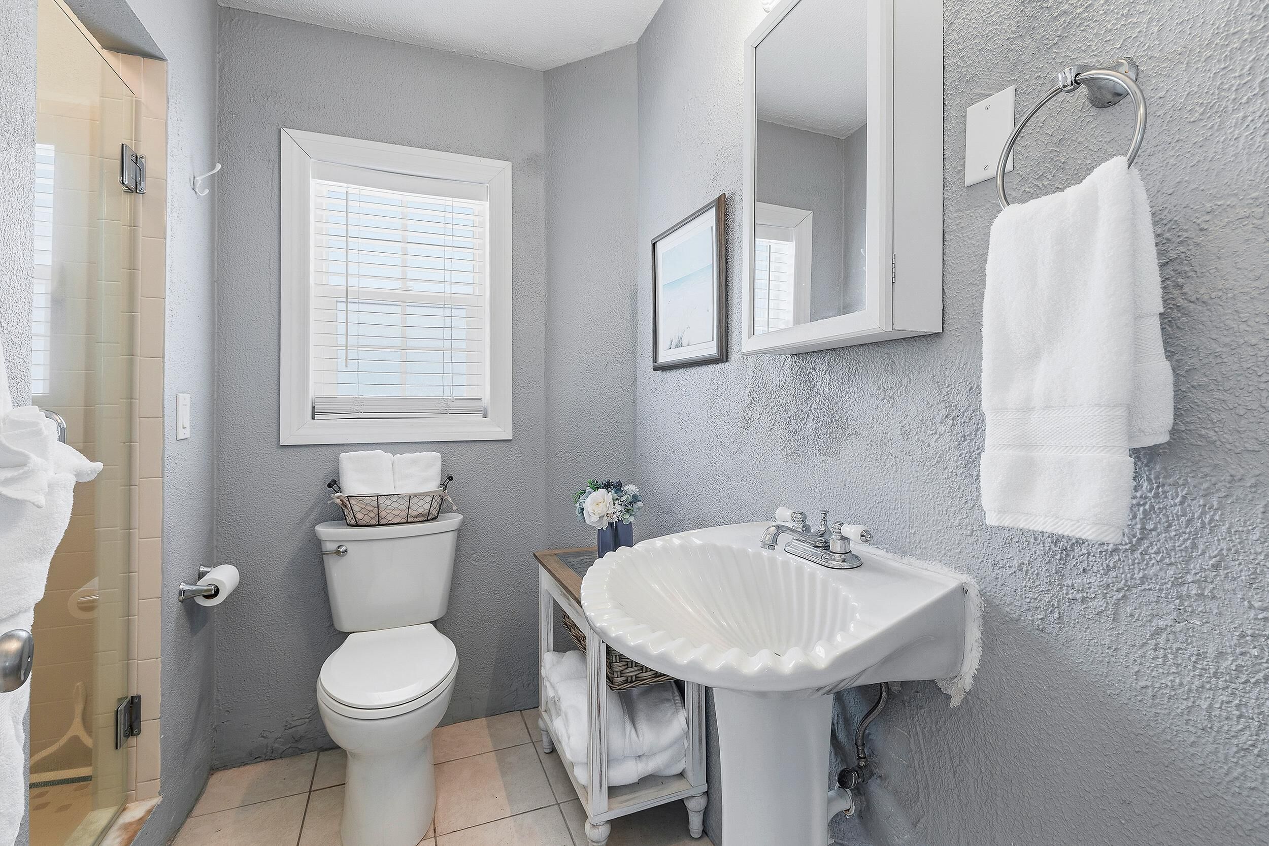 A bathroom with a toilet, sink, and window.