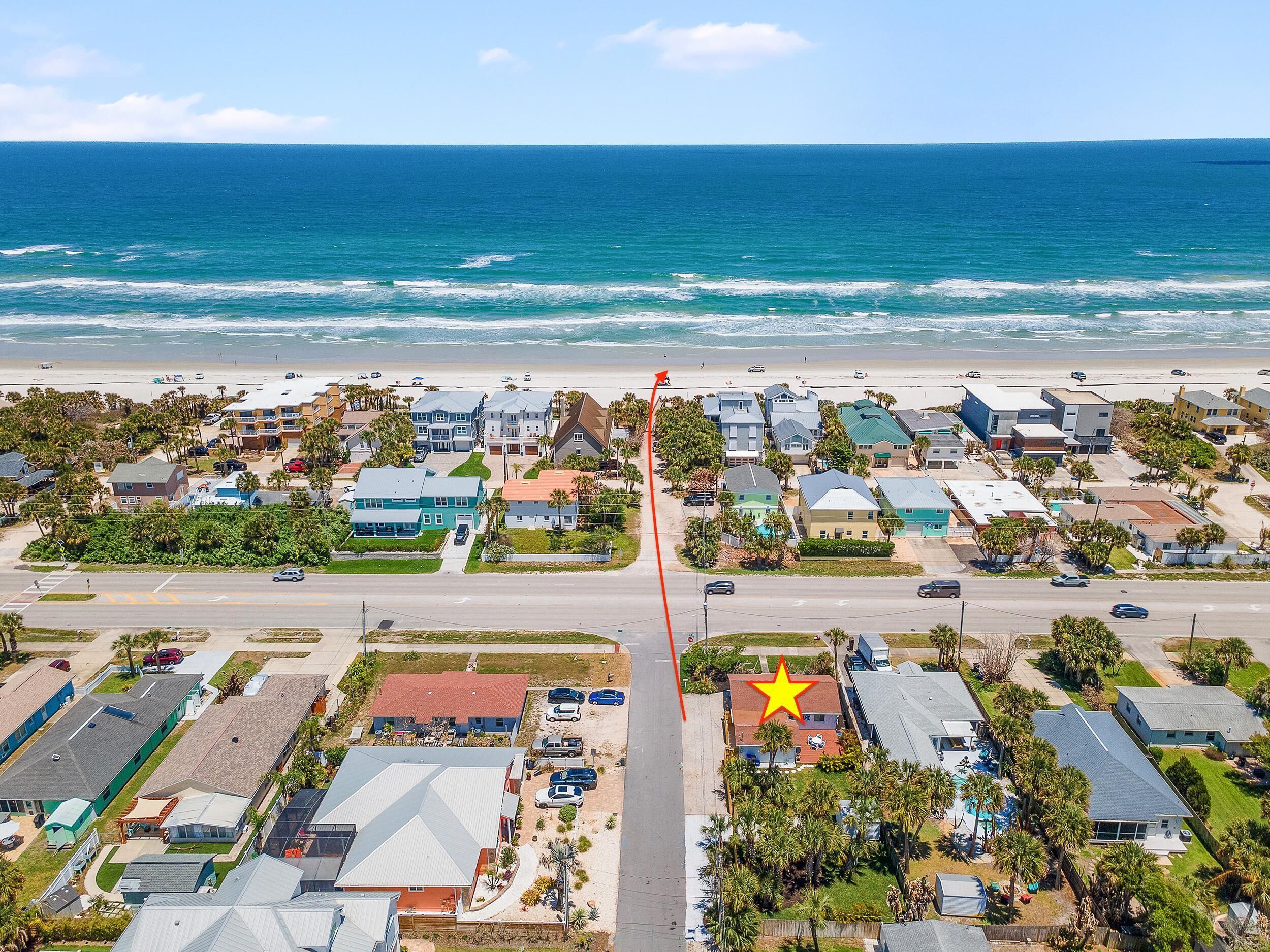 An aerial view of a coastal residential area with houses, a beach, and a star symbol marking a location.