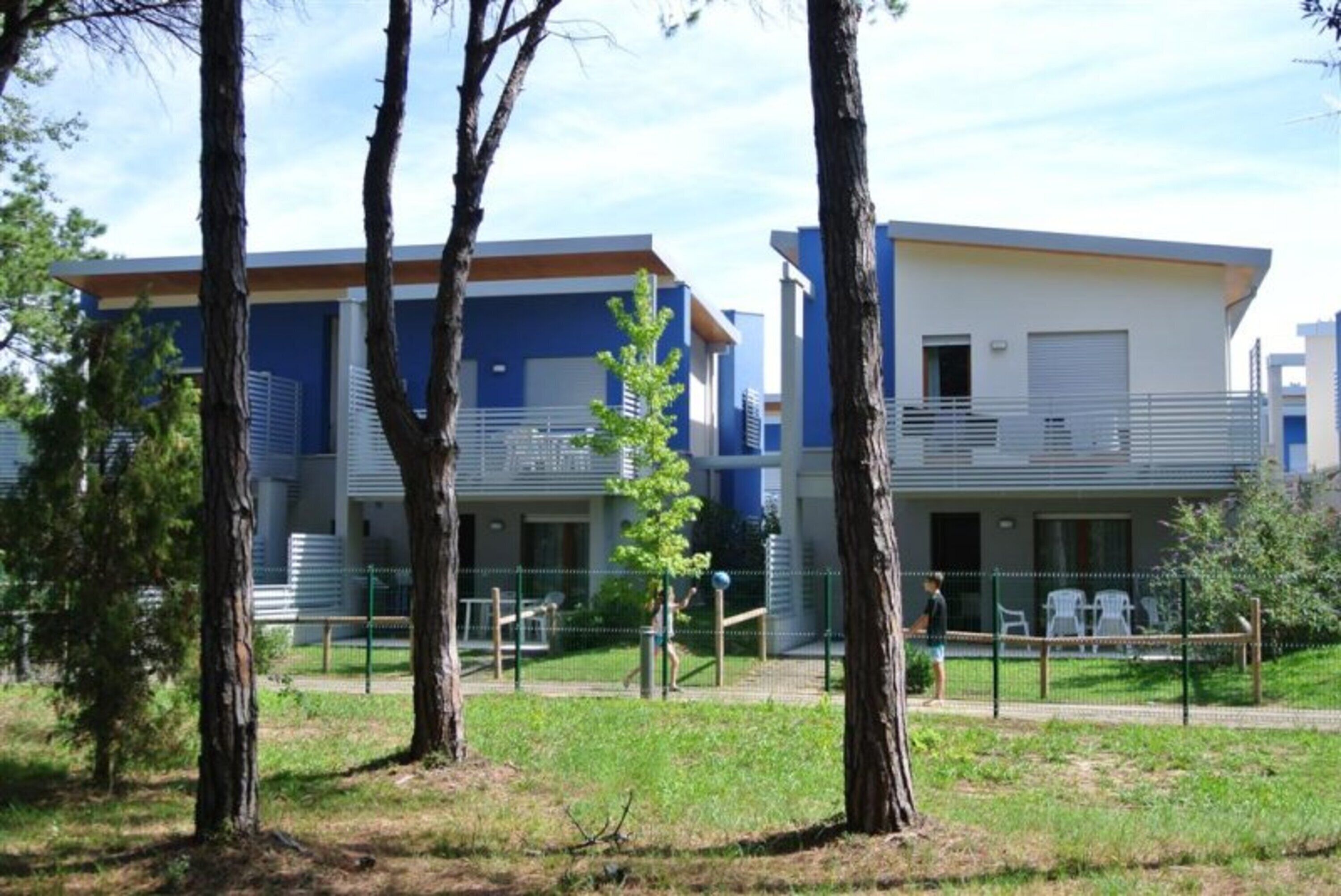 A modern building with a flat roof, large windows, and a balcony.