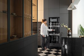 A modern kitchen with dark cabinetry, a checkered floor, and a vase with flowers on the counter. - Glam&Chic Sopot-City Centre with parking (Sopot)
