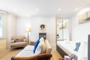 Una habitación de hotel moderna con sofá, cama, lámpara y obras de arte en las paredes.