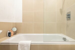 Un baño con bañera, un espejo y artículos de aseo en el mostrador.