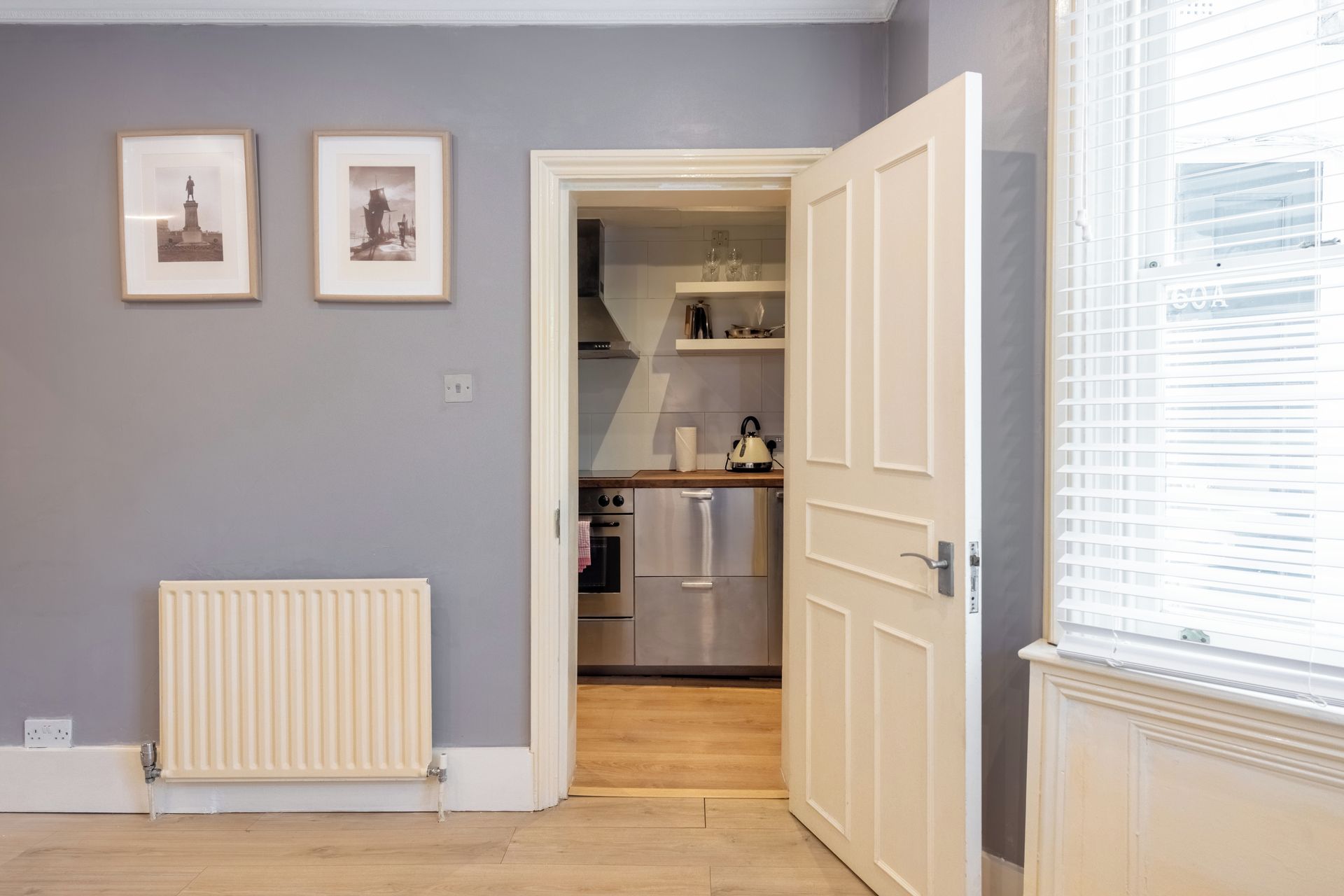 A kitchen with modern appliances, a radiator, and framed pictures on the wall.