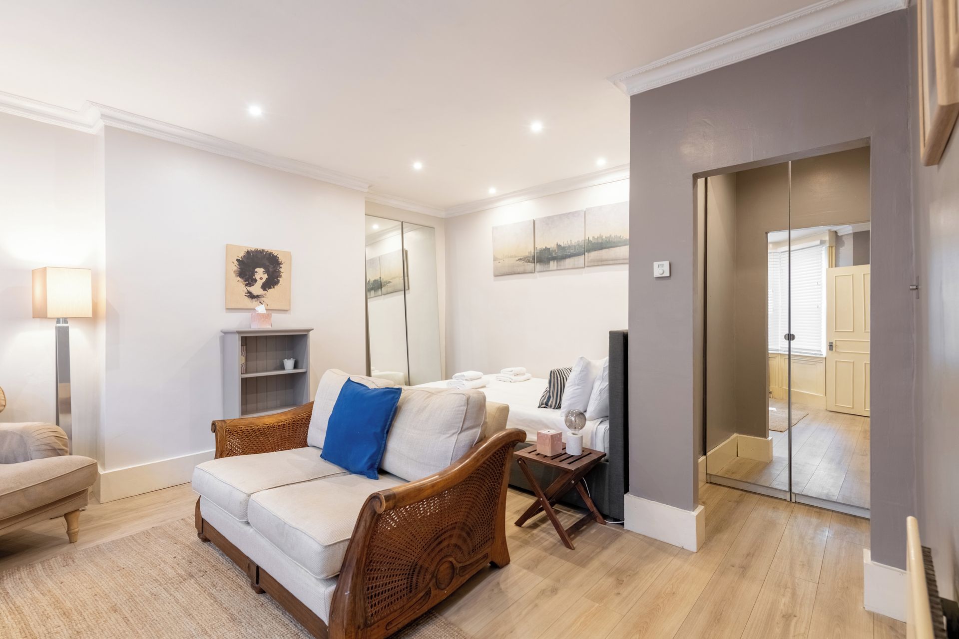 A modern living room with a sofa, a side table, a lamp, and artwork on the walls.